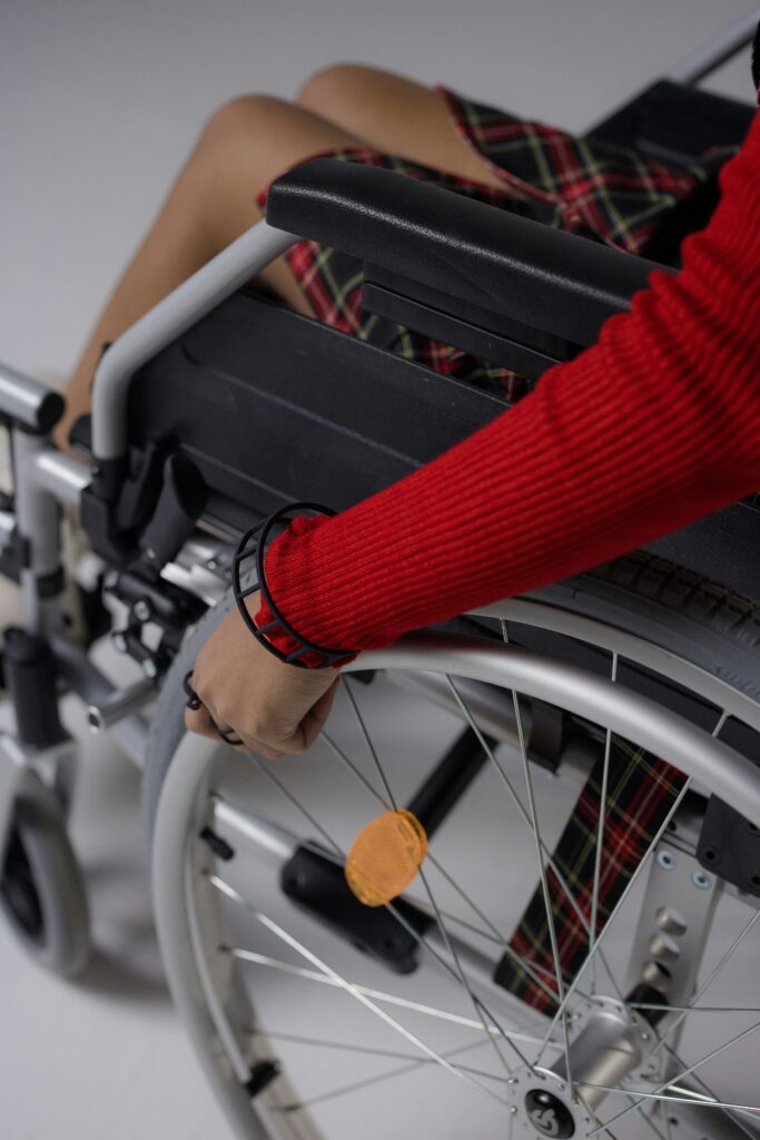 Close-up of a woman's hand on a wheelchair wheel with a red sleeve, symbolizing empowerment.